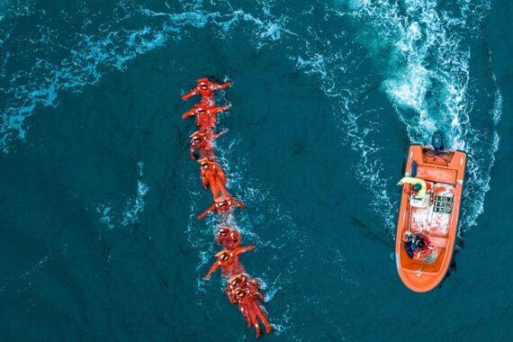Luftaufnahme von einem Rettungsboot und einer Menschenkette im Wasser