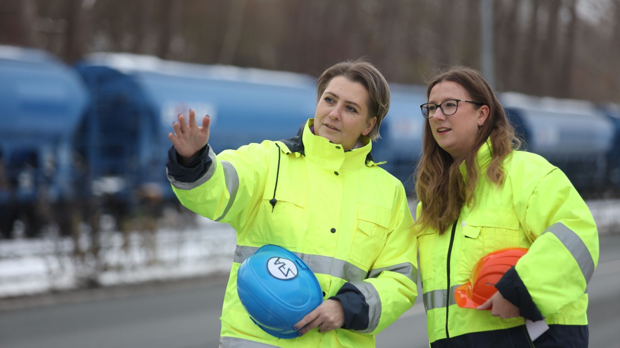Zwei Personen in Warnschutzkleidung sprechen vor Güterwaggons