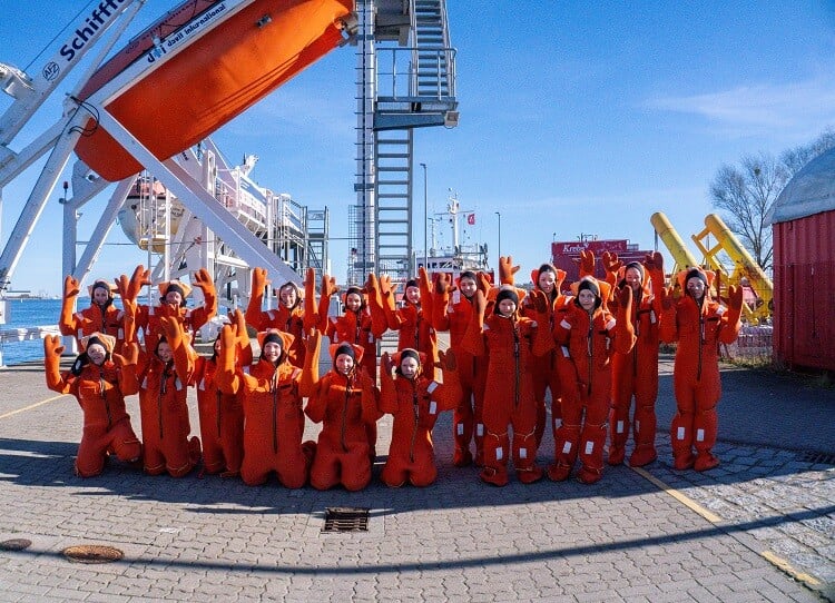 Girls Day Gruppenfoto in Überlebensanzügen vor dem Freifallboot des AFZ Rostock.