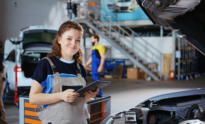 Auszubildende KFZ-Mechatronik mit einem Tablet in der Hand in einer KFZ Werkstatt